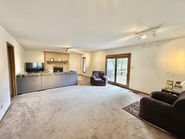 living area with carpet, a brick fireplace, rail lighting, and baseboards