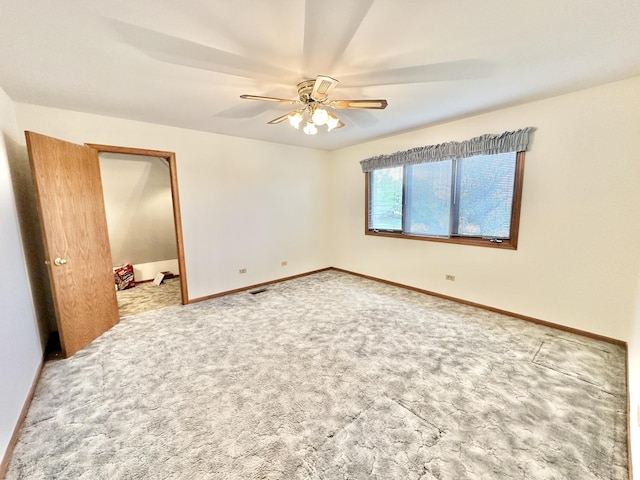 carpeted spare room with a ceiling fan and baseboards