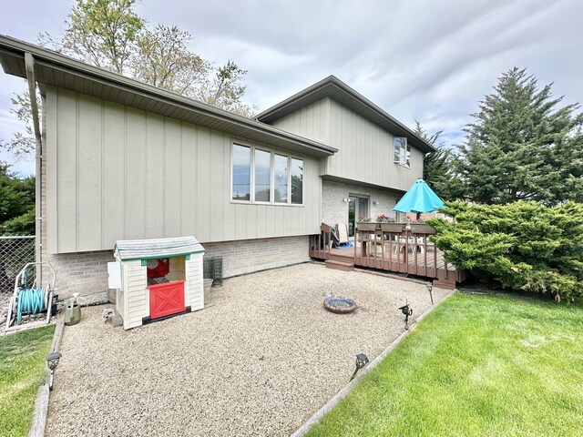 back of property featuring a wooden deck and a lawn