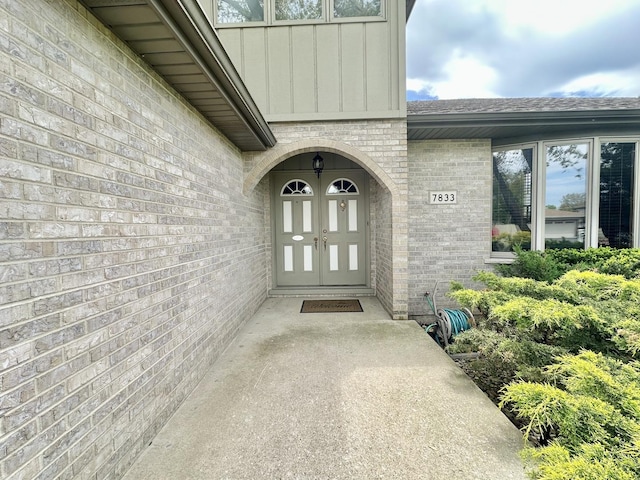 entrance to property with board and batten siding, brick siding, and roof with shingles