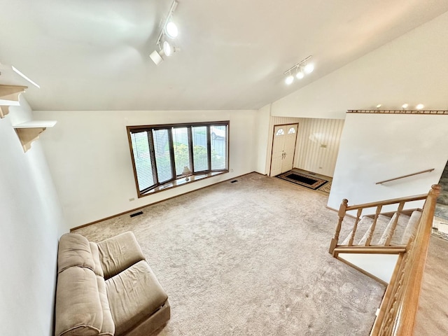 unfurnished living room with rail lighting, vaulted ceiling, and carpet flooring