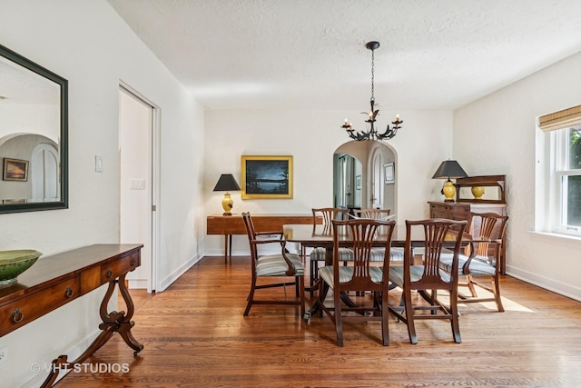 2037 Highland Ave, Wilmette, IL 60091 - dining space featuring arched walkways, wood finished floors, a textured ceiling, a chandelier, and baseboards