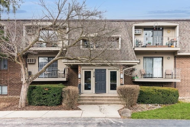 214 E Bailey Rd Unit J, Naperville, IL 60565 - view of front of home with a balcony, brick siding, and a wall mounted air conditioner