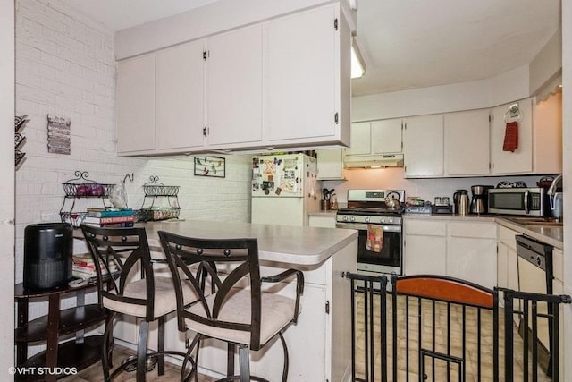 214 E Bailey Rd Unit J, Naperville, IL 60565 - kitchen with appliances with stainless steel finishes, under cabinet range hood, white cabinets, and a peninsula