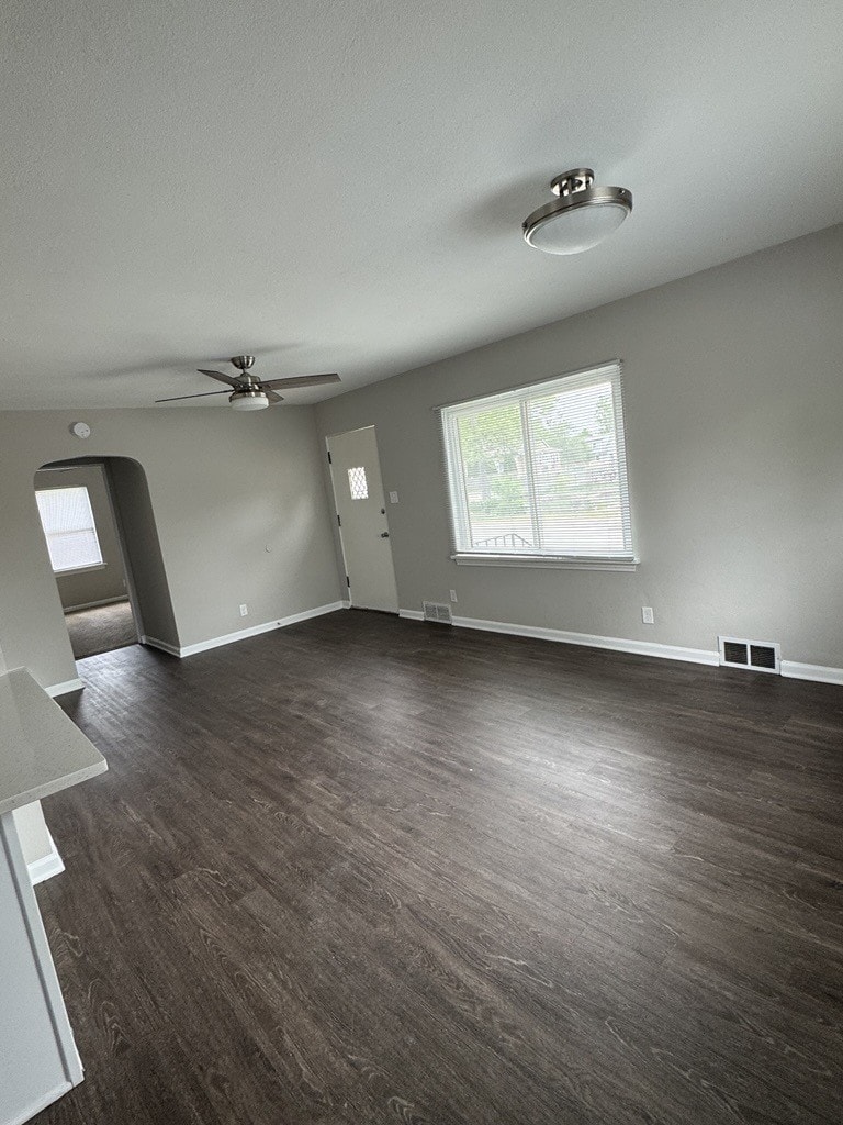 1600 Elgin Ave, Joliet, IL 60432 - unfurnished living room with dark wood-style floors, a ceiling fan, baseboards, arched walkways, and a textured ceiling