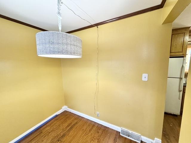 unfurnished dining area featuring ornamental molding, wood finished floors, and baseboards