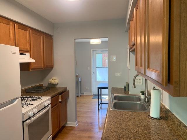 810 Skokie Blvd Unit C, Wilmette, IL 60091 - kitchen with white appliances, a sink, under cabinet range hood, brown cabinetry, and light wood-style flooring