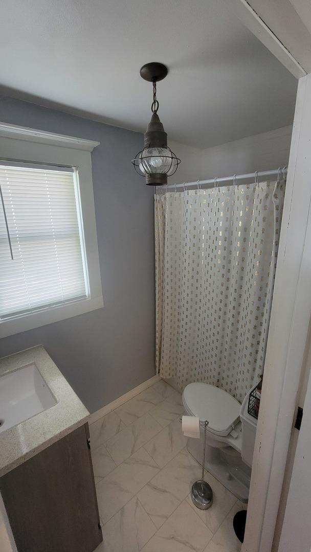401 Dixon Ave, Rock Falls, IL 61071 - bathroom featuring marble look tile flooring, vanity, toilet, baseboards, and curtained shower
