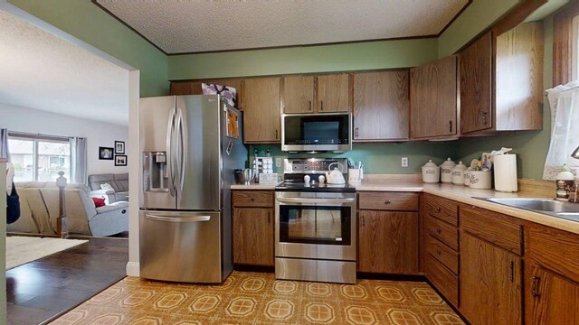 2702 Worcester Dr, Champaign, IL 61821 - kitchen with stainless steel appliances, light countertops, brown cabinetry, a textured ceiling, and open floor plan