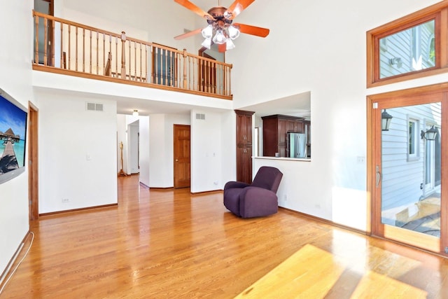 1337 E Thacker St, Schaumburg, IL 60173 - unfurnished living room with light wood-style flooring, a ceiling fan, a towering ceiling, and baseboards