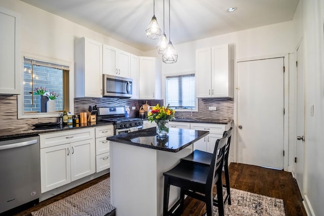 2512 N Marshfield Ave, Chicago, IL 60614 - kitchen with stainless steel appliances, a kitchen breakfast bar, dark wood-style flooring, and white cabinets