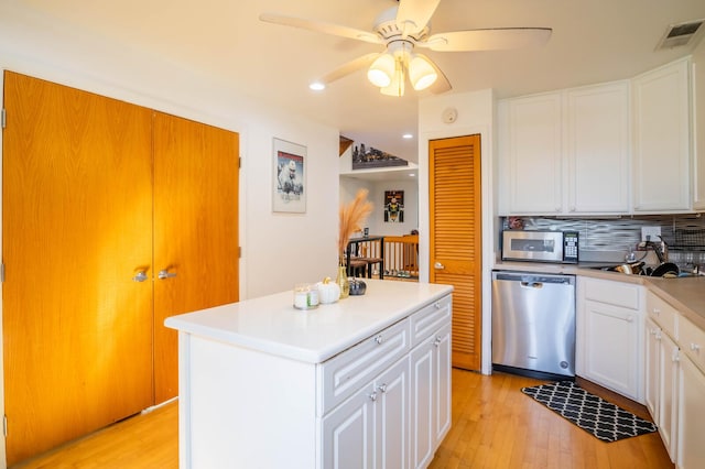 2512 N Marshfield Ave, Chicago, IL 60614 - kitchen featuring appliances with stainless steel finishes, a ceiling fan, light wood-type flooring, a center island, and white cabinetry