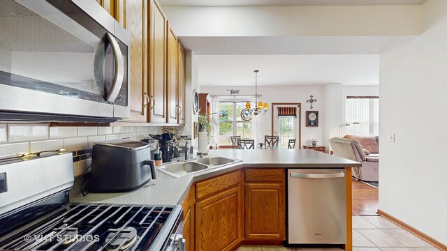 105 Grandview Ct, Volo, IL 60020 - kitchen with stainless steel appliances, a peninsula, brown cabinets, light tile patterned floors, and open floor plan