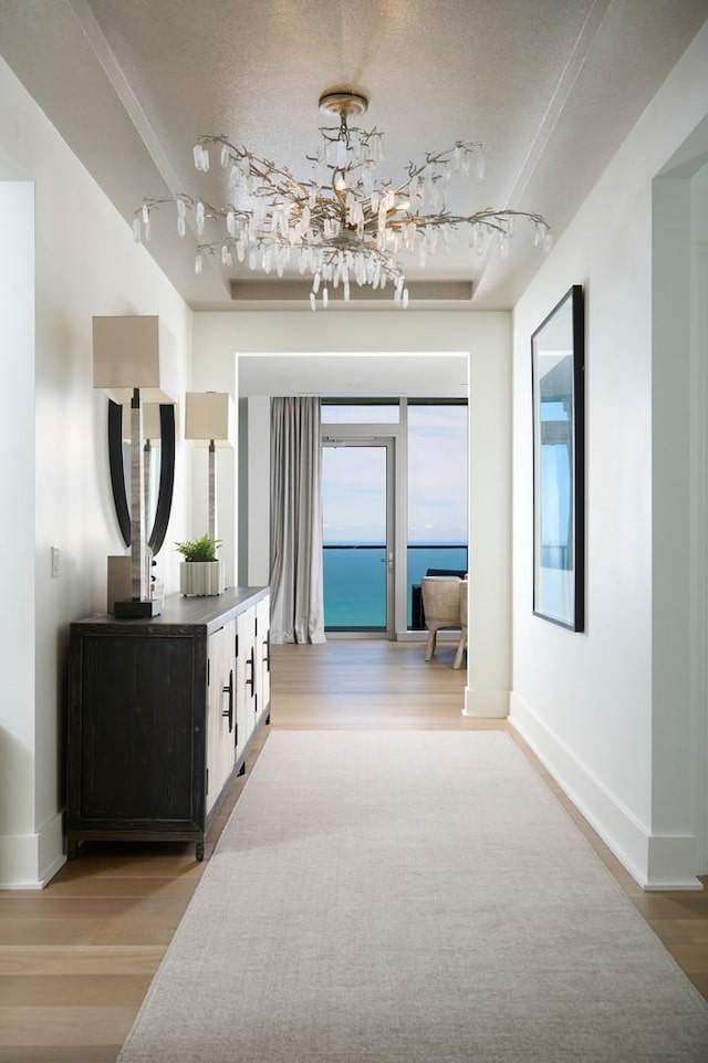 363 E Wacker Dr Unit 6106, Chicago, IL 60601 - hallway with track lighting, light wood finished floors, a chandelier, baseboards, and a textured ceiling