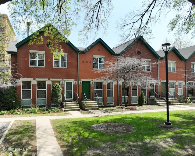 townhome / multi-family property featuring brick siding and a front yard