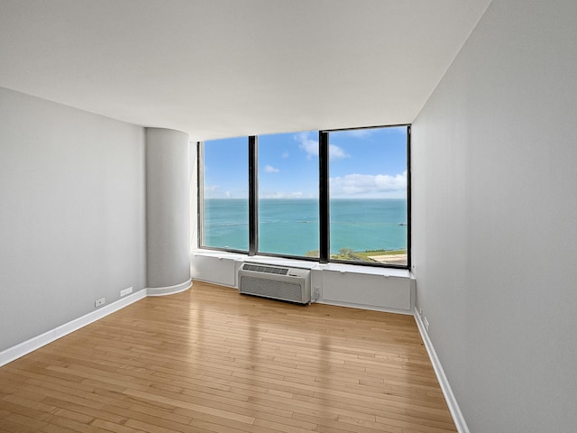 505 N Lake Shore Dr Unit 4105, Chicago, IL 60611 - empty room with light wood-type flooring, a wall mounted air conditioner, baseboards, and a water view