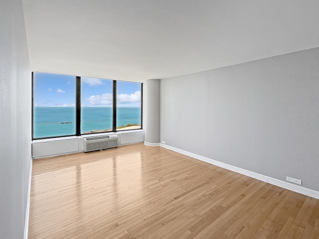 505 N Lake Shore Dr Unit 4105, Chicago, IL 60611 - unfurnished room featuring wood finished floors, a wall unit AC, a water view, and baseboards