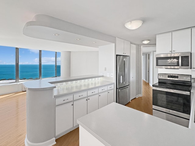 505 N Lake Shore Dr Unit 4105, Chicago, IL 60611 - kitchen featuring stainless steel appliances, a peninsula, light wood-style flooring, white cabinets, and light countertops