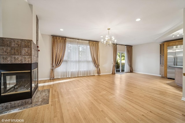 3305 Old Glenview Rd Unit A, Wilmette, IL 60091 - unfurnished living room featuring a tiled fireplace, a chandelier, light wood-style flooring, baseboards, and recessed lighting