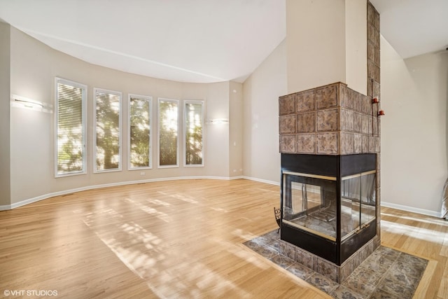3305 Old Glenview Rd Unit A, Wilmette, IL 60091 - unfurnished living room featuring light wood-type flooring, baseboards, vaulted ceiling, and a tile fireplace