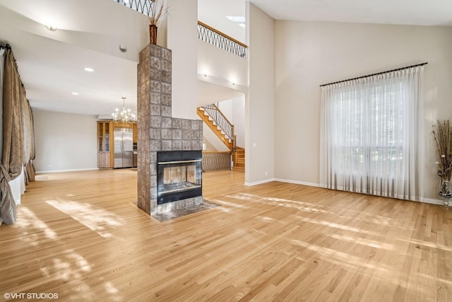 3305 Old Glenview Rd Unit A, Wilmette, IL 60091 - unfurnished living room featuring baseboards, high vaulted ceiling, wood finished floors, a tiled fireplace, and recessed lighting