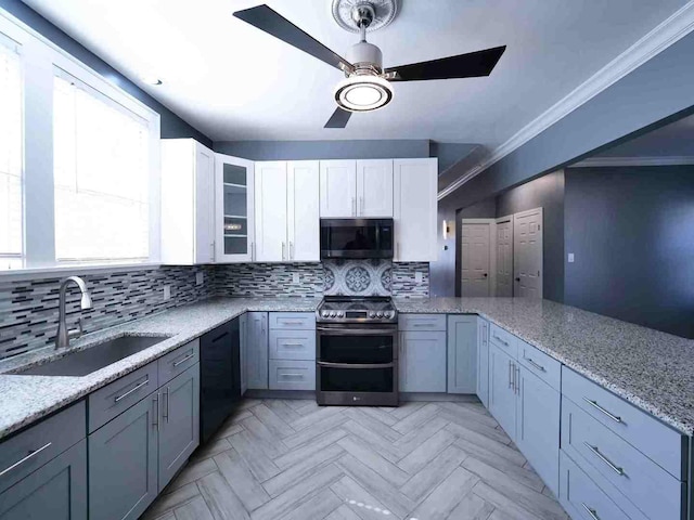 kitchen featuring appliances with stainless steel finishes, a sink, a ceiling fan, a peninsula, and backsplash