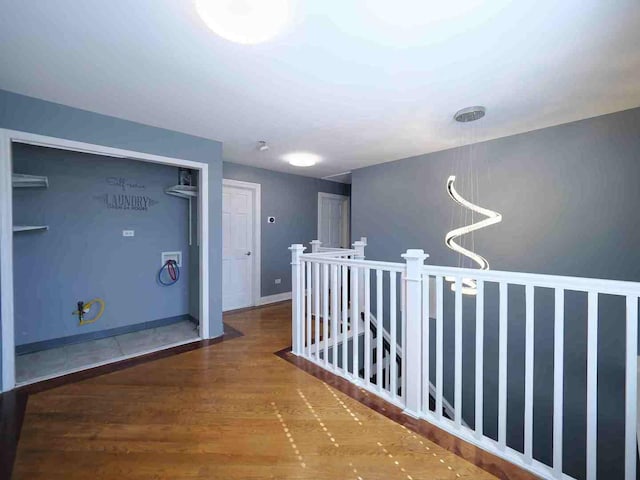 corridor with an upstairs landing, wood finished floors, and baseboards