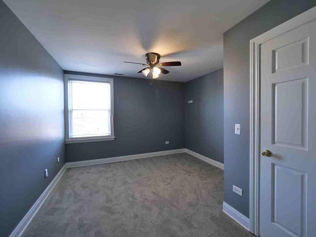 carpeted spare room with a ceiling fan and baseboards