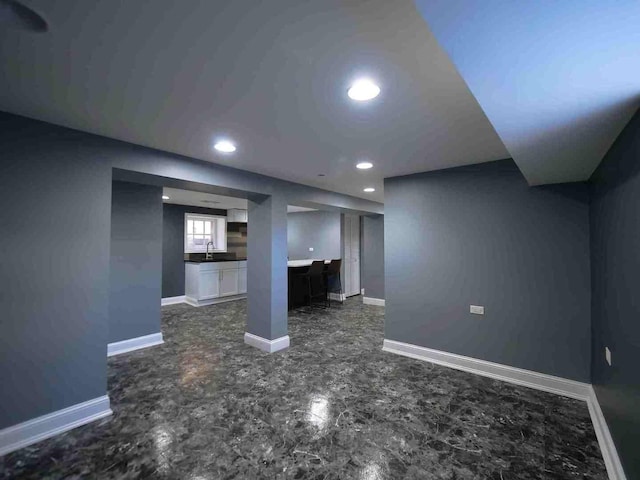 basement featuring recessed lighting, a sink, and baseboards