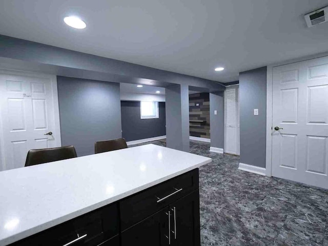 kitchen featuring light countertops, dark cabinets, recessed lighting, and baseboards