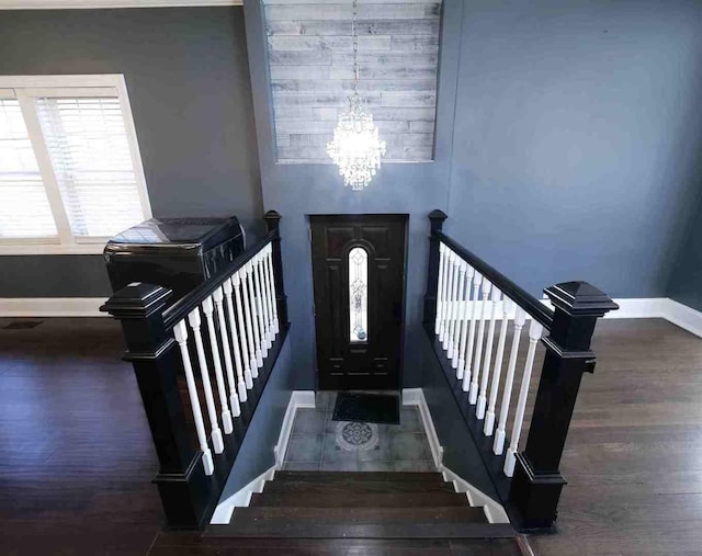 foyer featuring baseboards, a chandelier, wood finished floors, and stairs