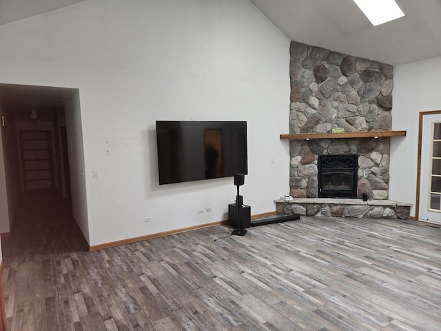 1988 S Chana Rd, Chana, IL 61015 - unfurnished living room featuring wood finished floors, high vaulted ceiling, a stone fireplace, and baseboards