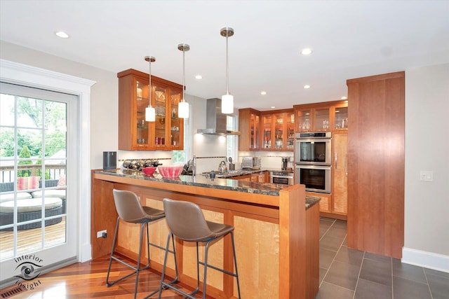616 E Hillside Ave, Barrington, IL 60010 - kitchen with wall chimney exhaust hood, stainless steel double oven, brown cabinets, glass insert cabinets, and recessed lighting