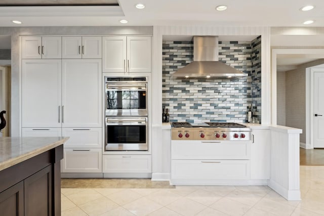 kitchen featuring stainless steel appliances, wall chimney exhaust hood, recessed lighting, tasteful backsplash, and light tile patterned floors