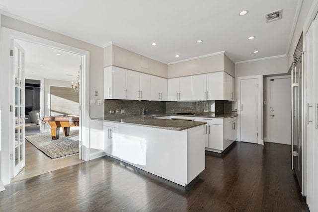 kitchen with decorative backsplash, crown molding, white cabinets, a peninsula, and recessed lighting