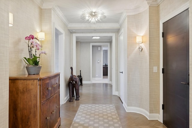 corridor with baseboards, crown molding, and a chandelier