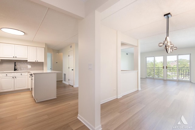 3940 W Bryn Mawr Ave Unit 403, Chicago, IL 60659 - kitchen with light wood finished floors, light countertops, backsplash, a chandelier, and white cabinetry