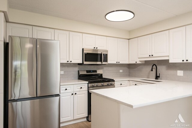 3940 W Bryn Mawr Ave Unit 403, Chicago, IL 60659 - kitchen with stainless steel appliances, a peninsula, a sink, white cabinets, and backsplash