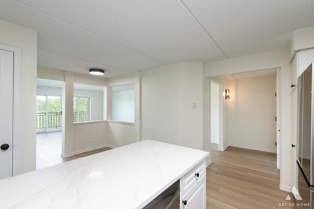 3940 W Bryn Mawr Ave Unit 403, Chicago, IL 60659 - kitchen with light wood finished floors, light stone countertops, baseboards, and white cabinetry