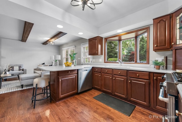 570 E Carpenter Dr, Palatine, IL 60074 - kitchen with appliances with stainless steel finishes, a peninsula, a kitchen breakfast bar, light countertops, and dark wood-type flooring