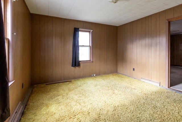 carpeted spare room with a baseboard radiator and wood walls