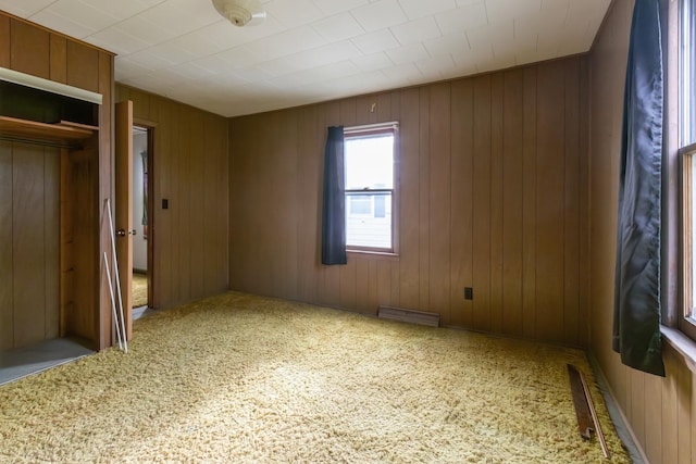 unfurnished bedroom featuring wooden walls, a closet, and carpet flooring