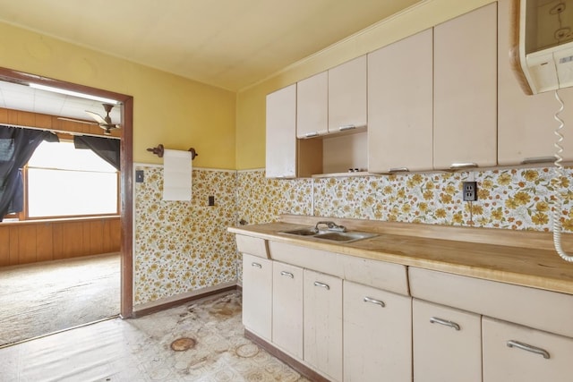 kitchen featuring a sink, light countertops, lofted ceiling, and a wainscoted wall