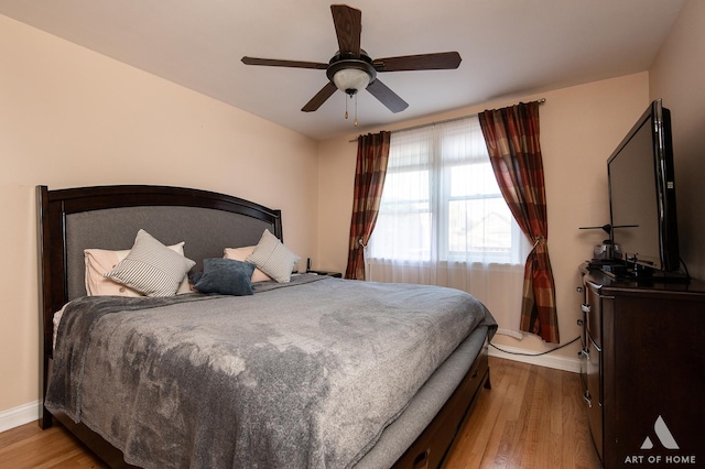 bedroom featuring baseboards, light wood-style floors, and a ceiling fan