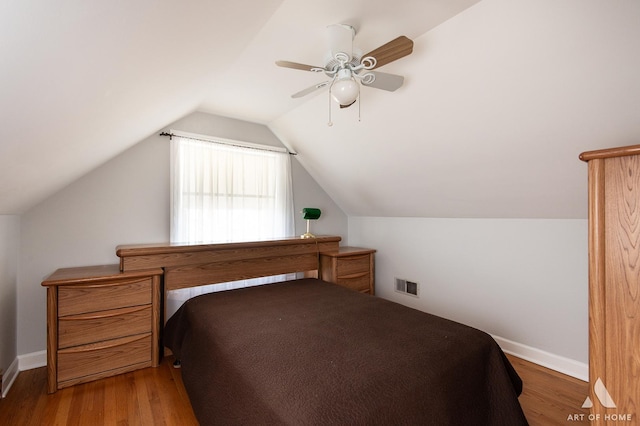 bedroom with wood finished floors, a ceiling fan, lofted ceiling, and baseboards