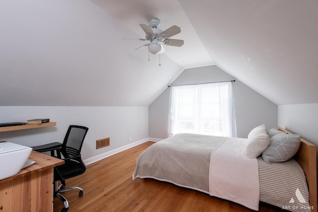bedroom featuring wood finished floors, lofted ceiling, baseboards, an office area, and a ceiling fan