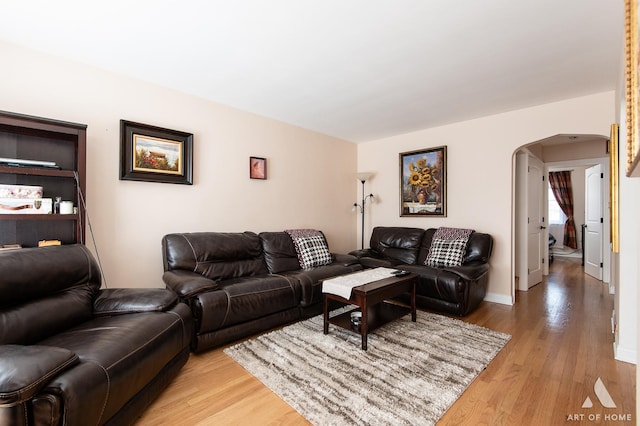 living room featuring arched walkways and light wood-type flooring