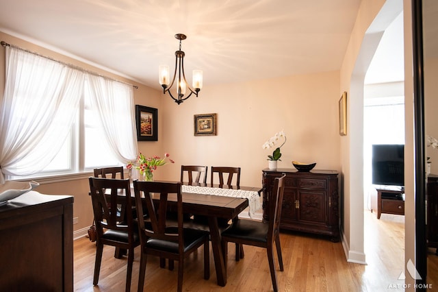 dining room featuring a chandelier, light wood-style flooring, and baseboards