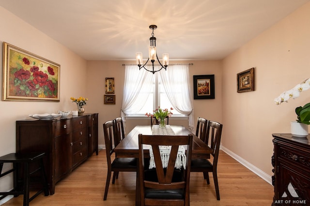 dining area featuring a chandelier, light wood-style floors, and baseboards
