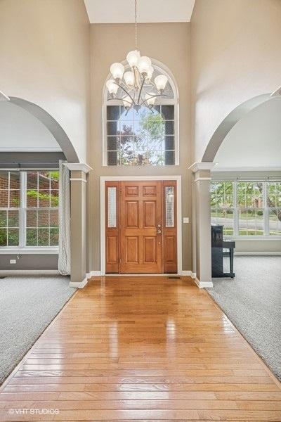 218 Bridle Path Ln, Fox River Grove, IL 60021 - entrance foyer with arched walkways, a high ceiling, hardwood / wood-style flooring, a chandelier, and ornate columns